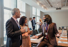 Small group of business men and women talking before a conference.